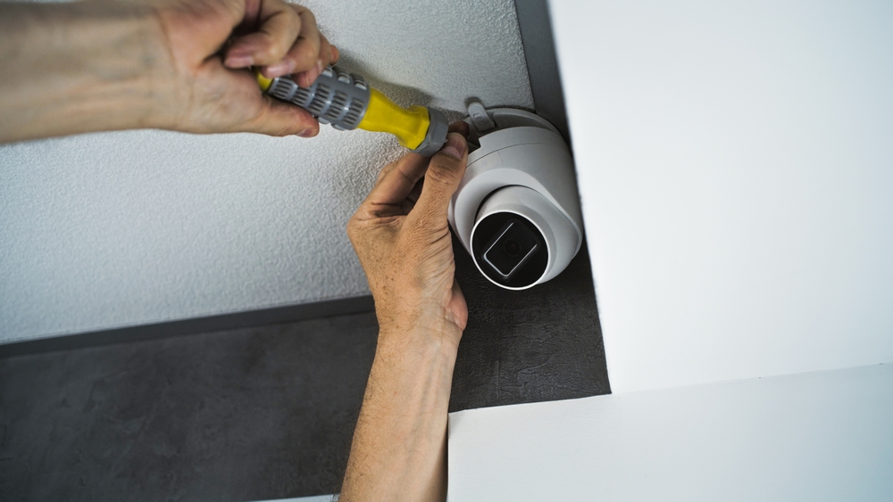 Technician mounting a PoE security camera on a Brampton home